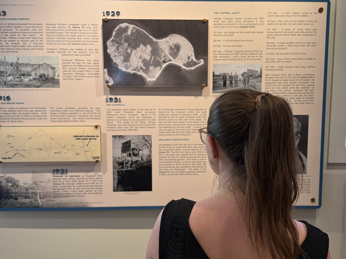 A visitor reading through the timeline of the Oak Island search on the Interpretive Centre’s history wall